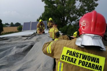 Strażacy przykrywają uszkodzony dach folią