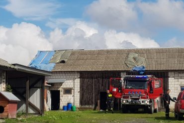 Wóz strażacki przy zabezpieczonym dachu budynku gospodarczego