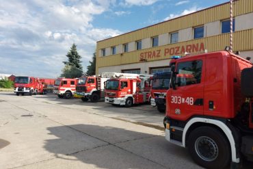 Strażacy z Komendy Miejskiej Państwowej Straży Pożarnej w Lublinie uruchamiają sygnały dźwiękowe i świetlne wyjeżdżając samochodami bojowymi przed garaż