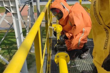 Strażacy ze Specjalistycznej Grupy Chemicznej PSP w kombinezonach gazoszczelnych usuwają wyciech z instalacji przesyłowej ciekłego amoniaku