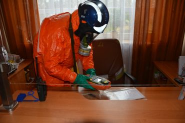 Strażak ubrany w kombinezon chemiczny podczas lokalizacji substancji niebezpiecznej