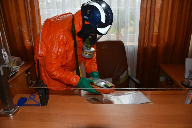 Strażak ubrany w kombinezon chemiczny podczas lokalizacji substancji niebezpiecznej