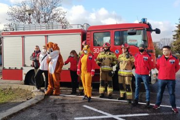 Strażacy, ratownicy medycznie oraz przedstawiciele PCK stoją przed samochodem ratowniczo-gaśniczym PSP