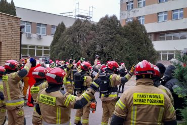 Strażacy machający do dzieci wyglądających przez okna szpitala