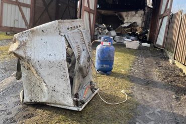 Rumowisko budynków gospodarczych po wybuchu gazu. Na pierwszym planie zniszczona kuchenka gazowa i butla